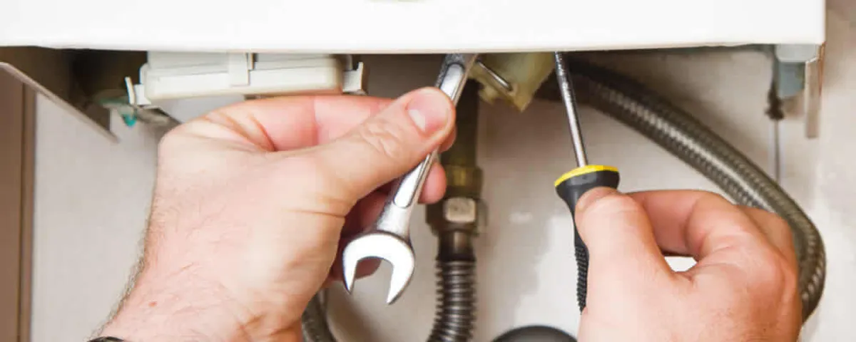 Boiler repair technician tightening pipe fittings and connections in Phoenix, AZ