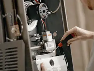 Furnace repair technician inspecting internal components and wiring in Phoenix, AZ