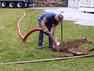 Septic pumping technician servicing a residential septic tank with a vacuum hose in Phoenix, AZ