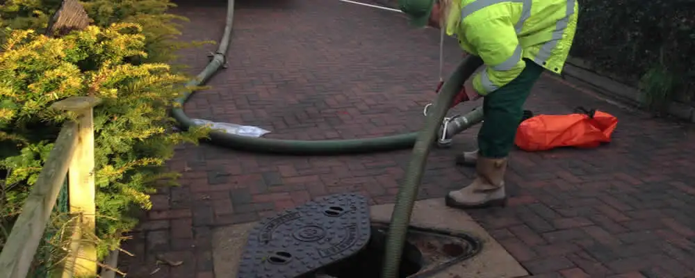 Septic tank cleaning technician servicing a septic tank with a vacuum hose in Phoenix, AZ