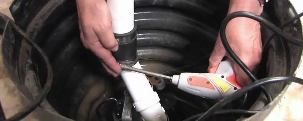 Sump pump installation technician connecting PVC discharge piping in Phoenix, AZ