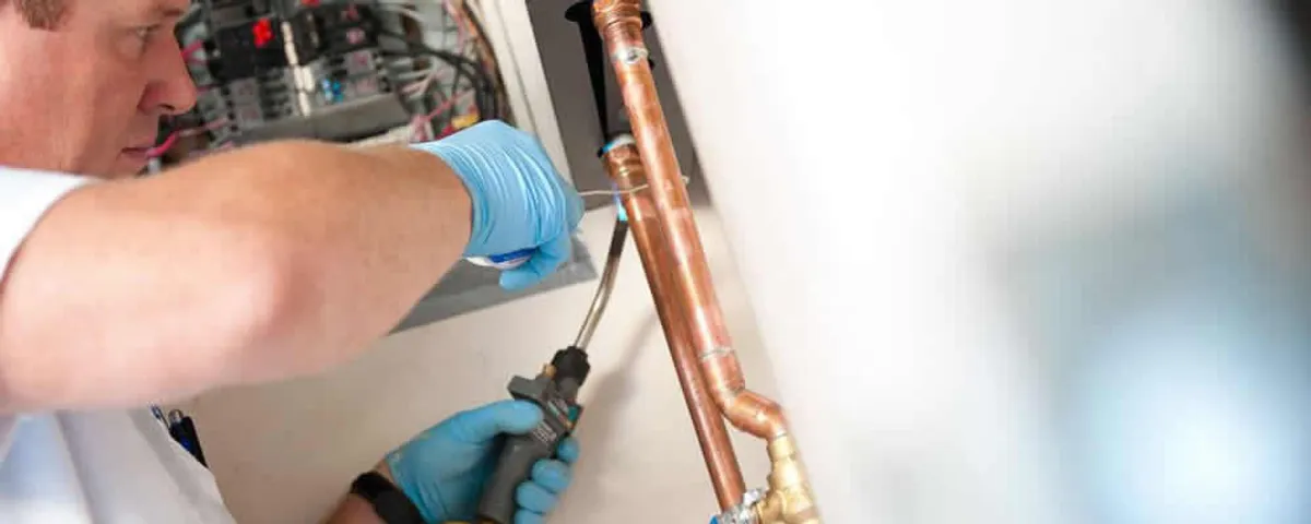 Water heater repair technician testing copper pipe connections and controls in Phoenix, AZ
